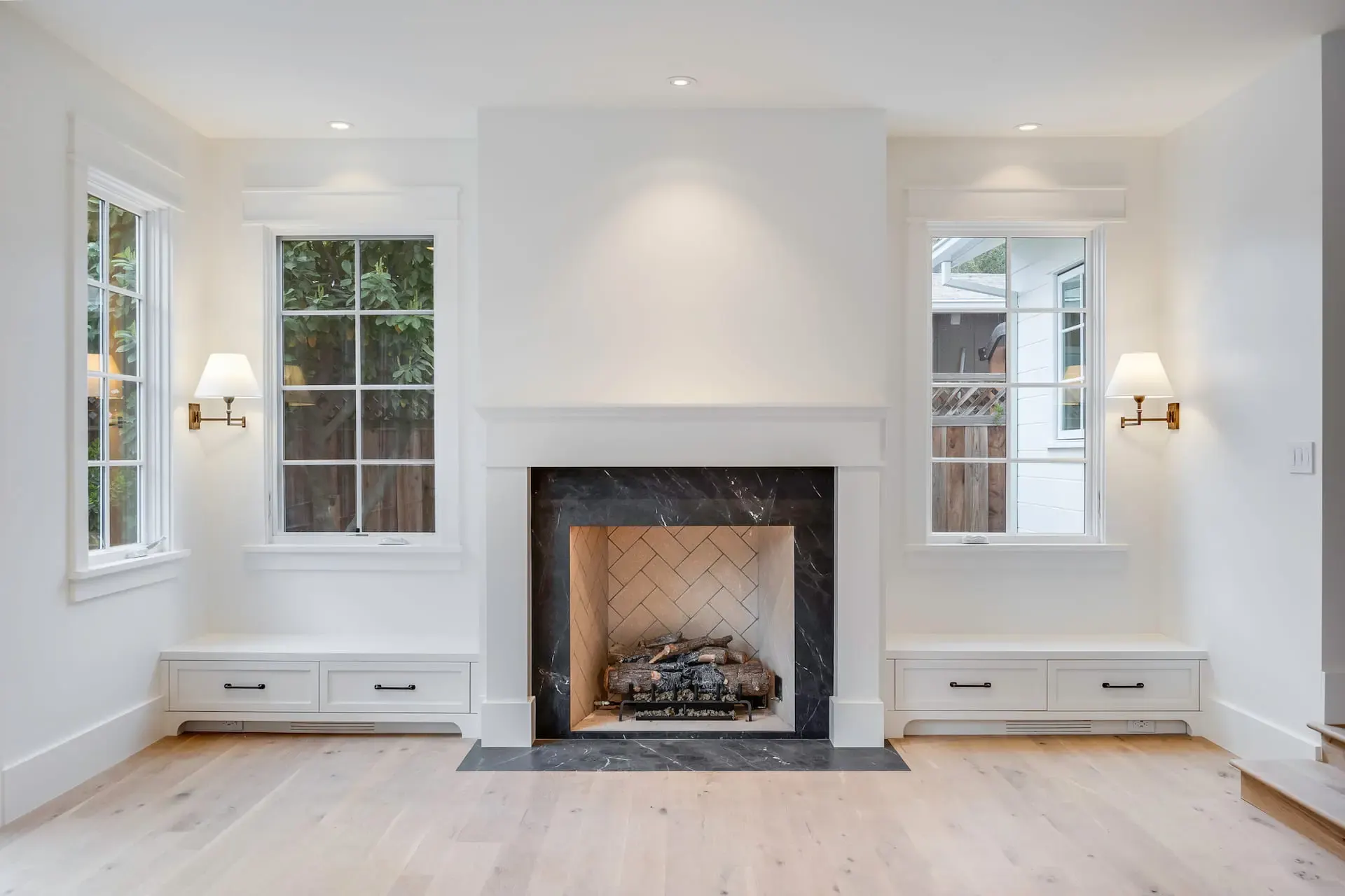 A quiet room with daylight from tall windows and a fireplace